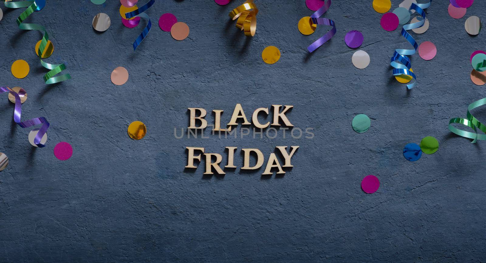Banner with Black Friday text and holiday tinsel flat lay on dark background. by ssvimaliss
