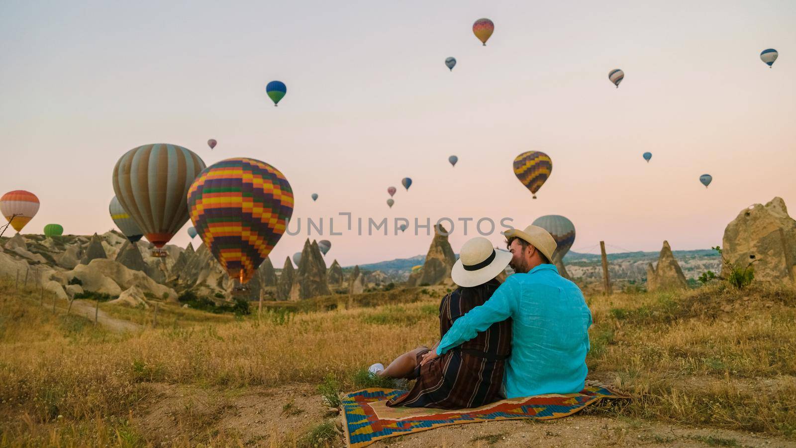 happy young couple during sunrise watching the hot air balloons of Kapadokya Cappadocia Turkey by fokkebok