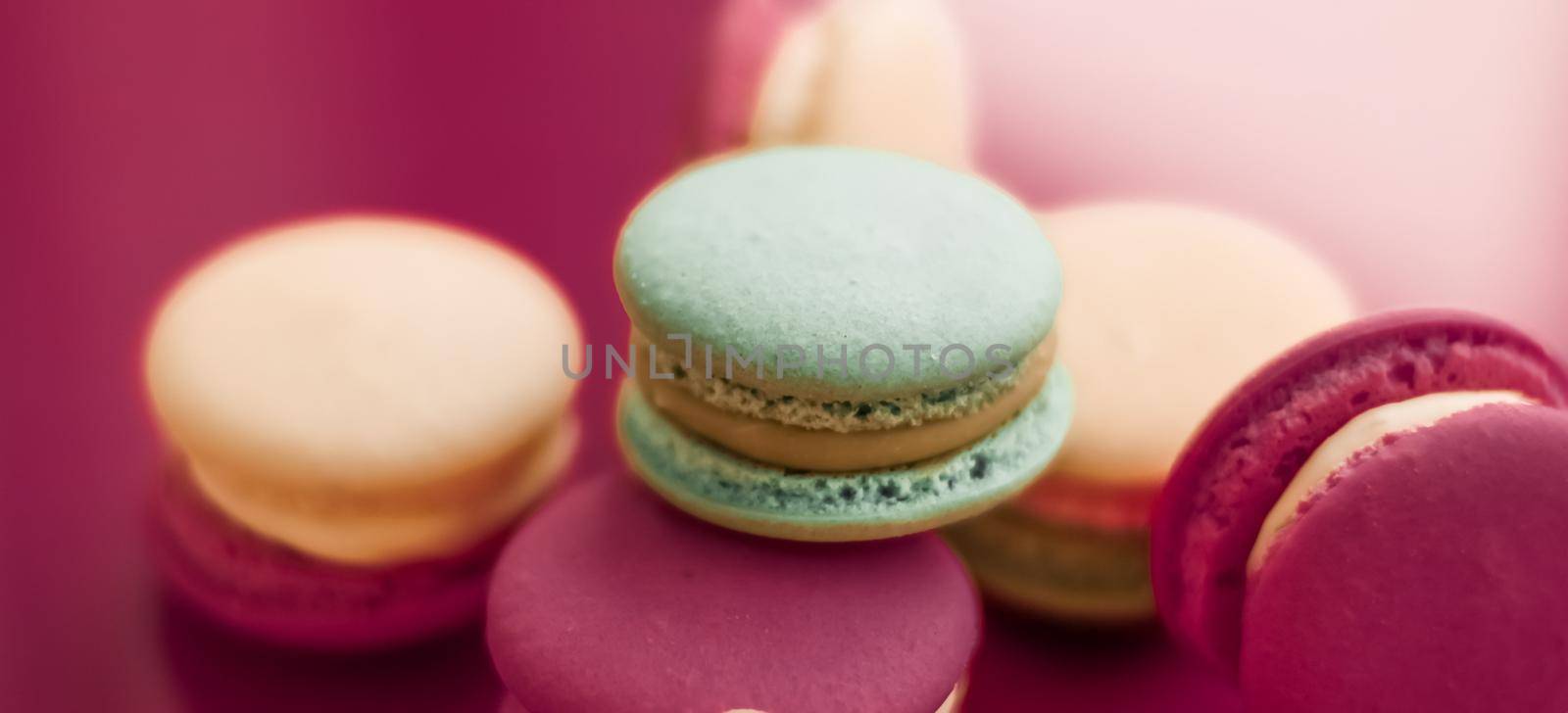 Pastry, bakery and branding concept - French macaroons on cherry pink background, parisian chic cafe dessert, sweet food and cake macaron for luxury confectionery brand, holiday backdrop design