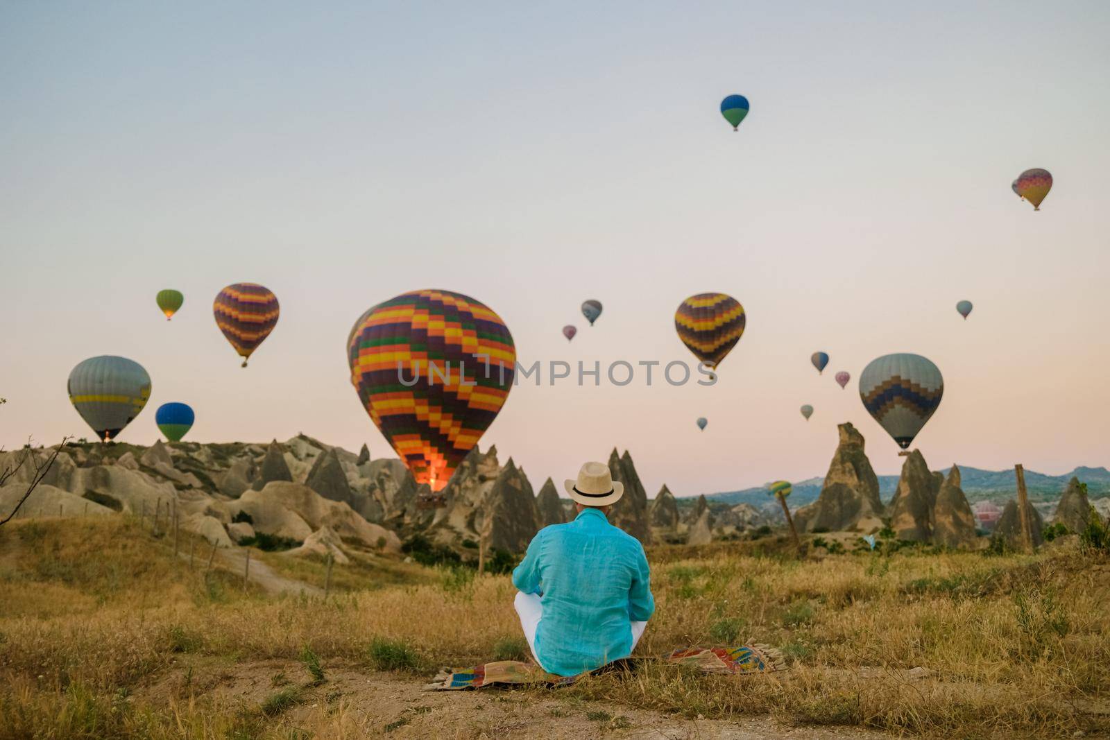 Young men watching hot air balloons during sunrise in Cappadocia Turkey, Kapadokya Goreme. Young caucasian men watching the sunrise in the valley of Cappadocia Turkey