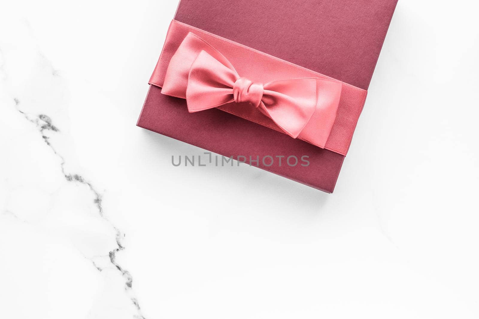 Birthday, wedding and girly branding concept - Coral gift box with silk bow on marble background, girl baby shower present and glamour fashion gift for luxury beauty brand, holiday flatlay art design