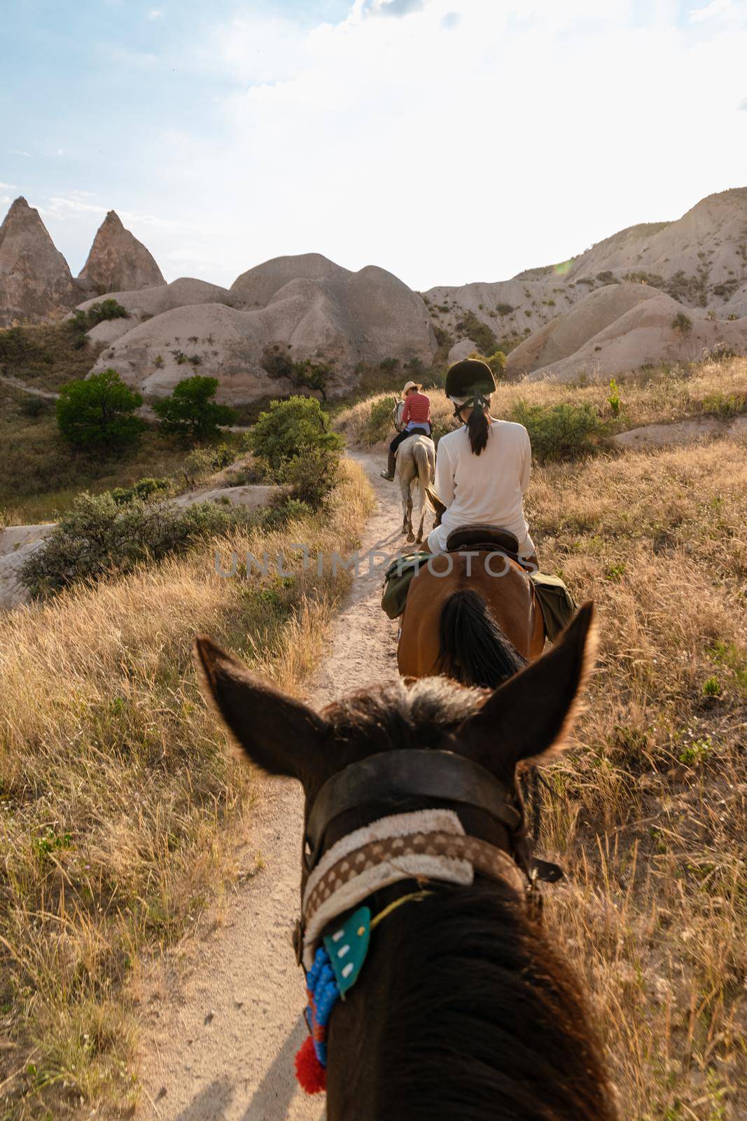 young woman during a vacation in Turkey Kapadokya watching the hot air balloons of Cappadocia. Asian women on the back of a brown horse in the valley of Cappadocia
