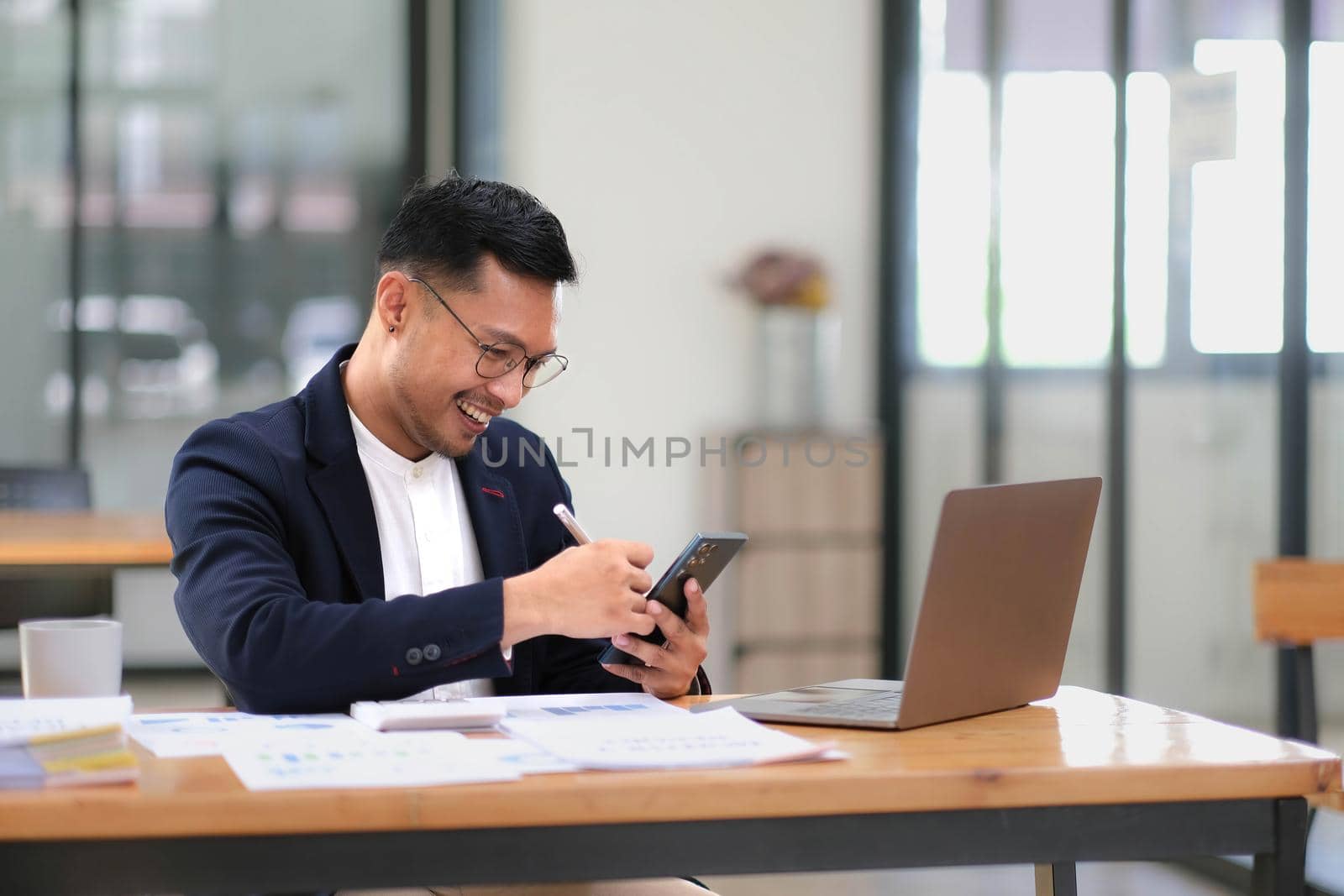 Portrait of a male business owner showing a happy smiling face as he has successfully invested his business using computers