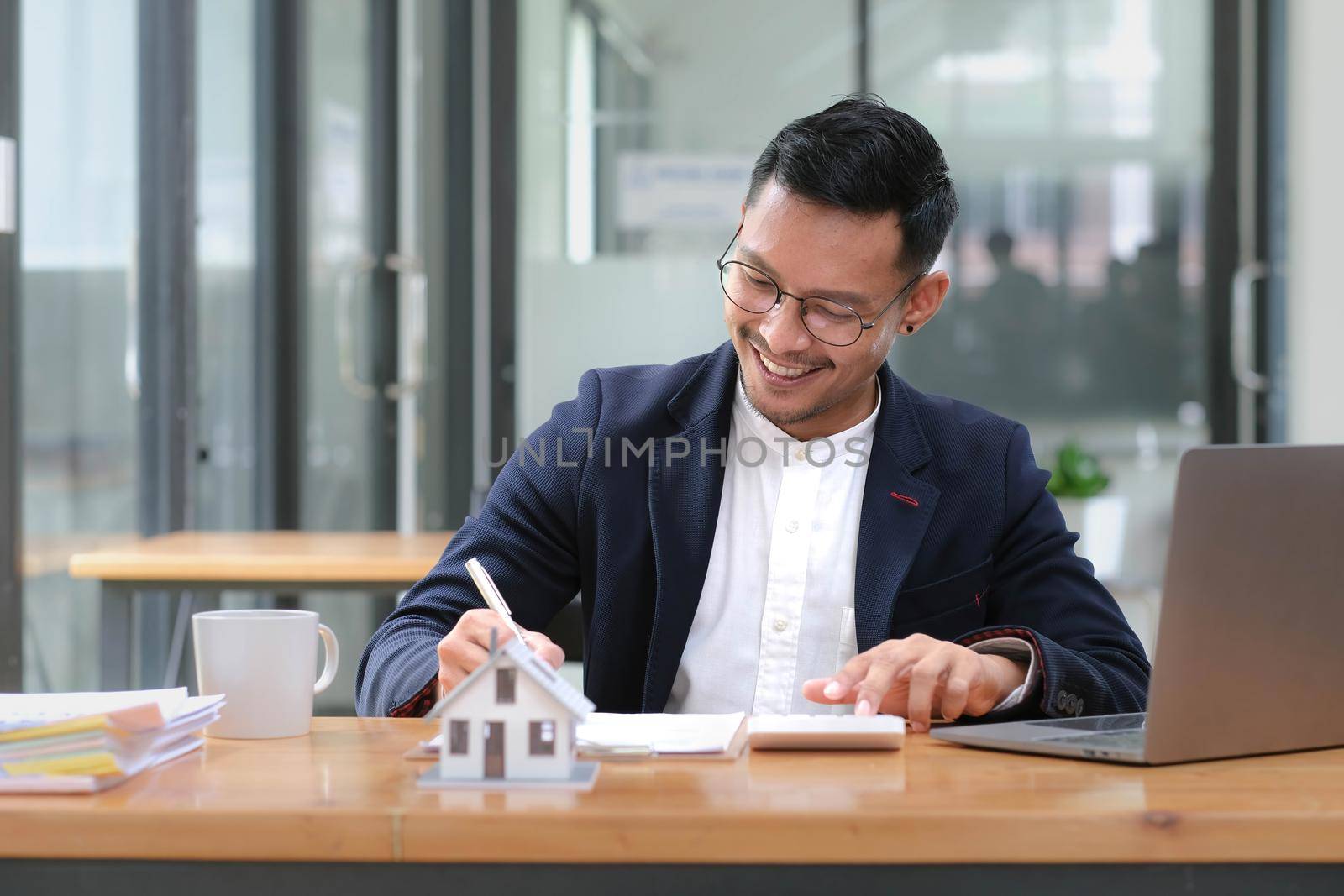 House model with agent business man signs a purchase contract or mortgage for a home, buy and sell home insurance concerning mortgage loan Real estate concept. by wichayada