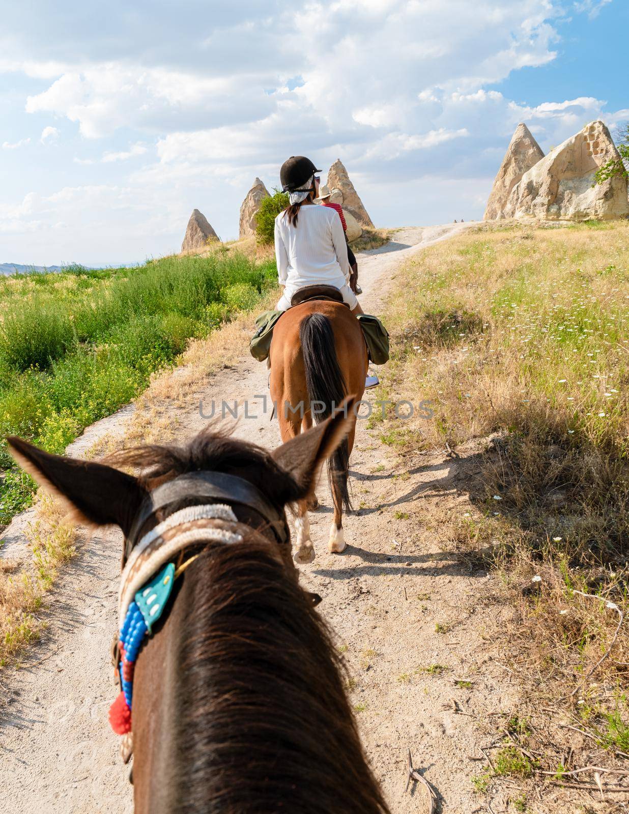 young woman during a vacation in Turkey Kapadokya watching the hot air balloons of Cappadocia. Asian women on the back of a brown horse in the valley of Cappadocia