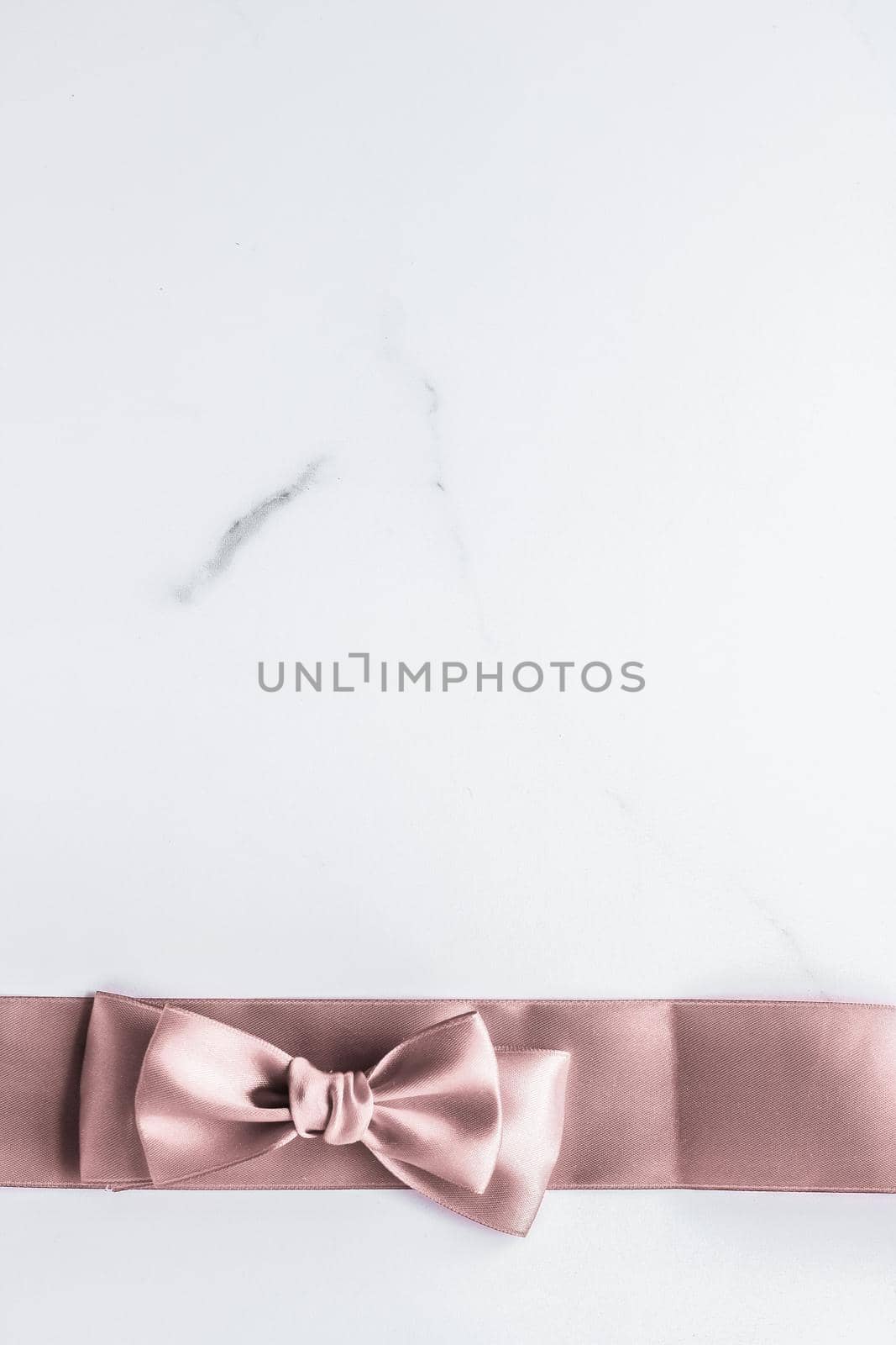 Birthday, wedding and girly branding concept - Beige silk ribbon and bow on marble background, glamour present mockup and fashion gift decoration for luxury beauty brand holiday flatlay design