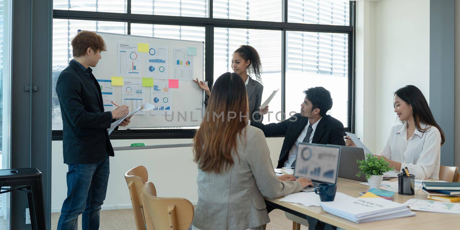 Group of diverse colleagues discussing for financial report with presentation on flipchart during a small conference in the office.