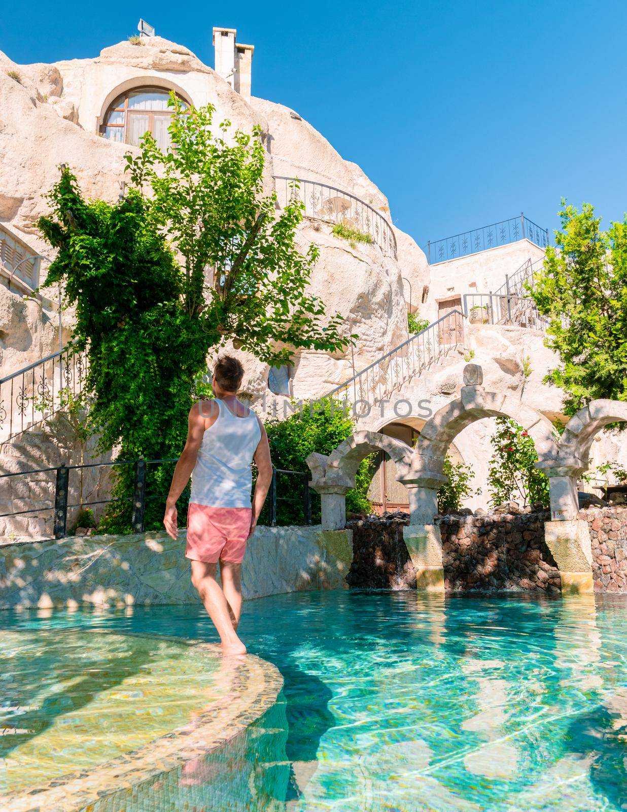 woman in dress at cave house , guy in infinity pool cave house hotel in the mountains of Cappadocia by fokkebok