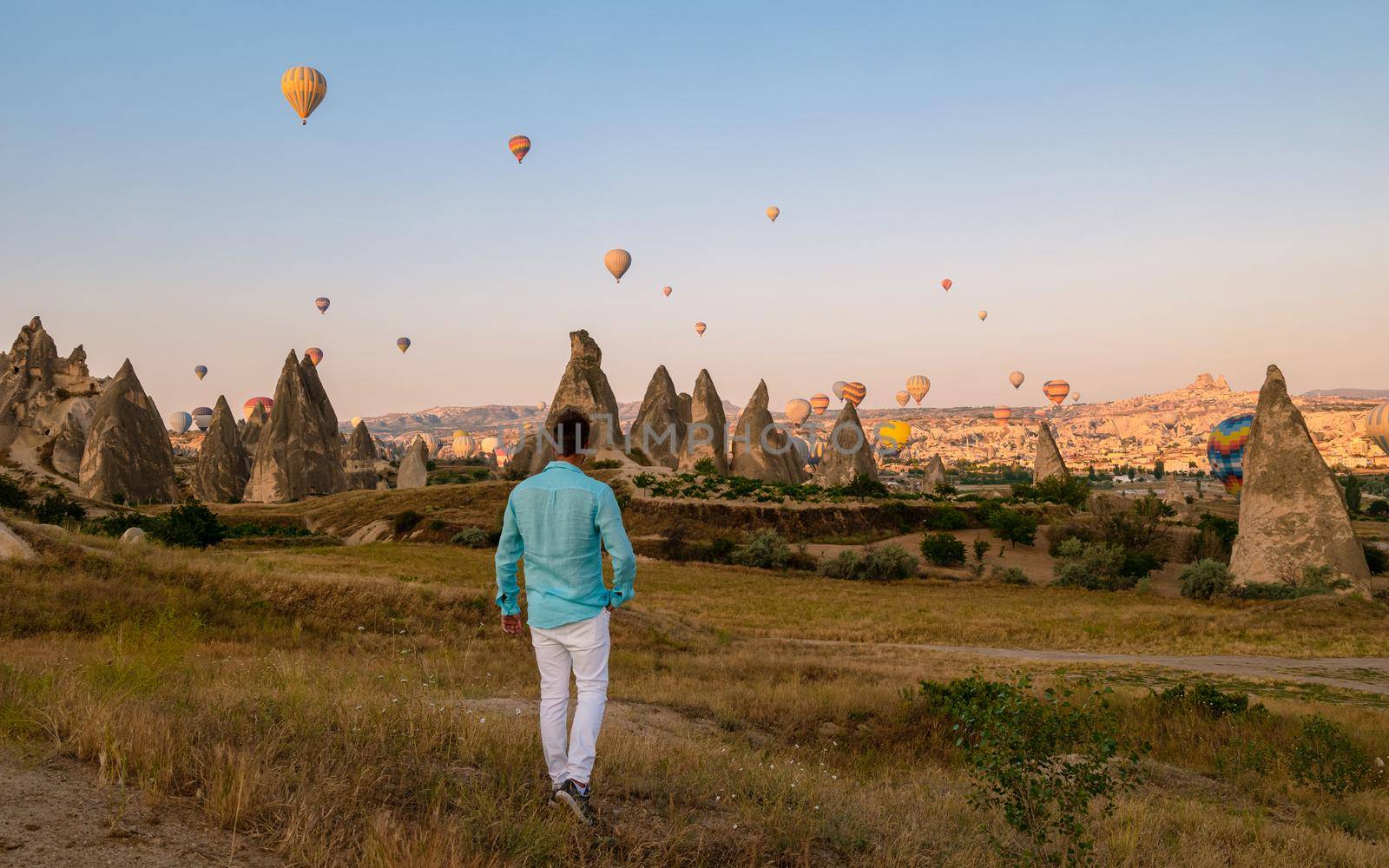 Young men watching hot air balloons during sunrise in Cappadocia Turkey, Kapadokya Goreme. Young caucasian men watching the sunrise in the valley of Cappadocia Turkey