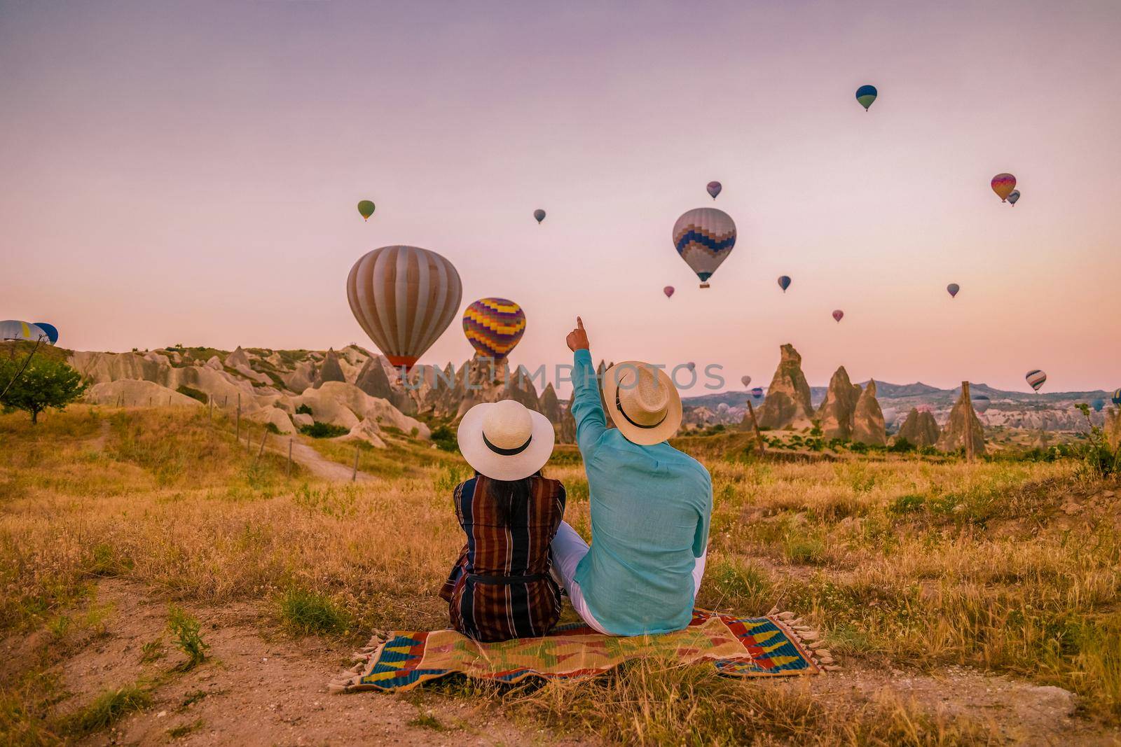 happy young couple during sunrise watching the hot air balloons of Kapadokya Cappadocia Turkey by fokkebok