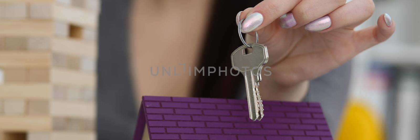 Female worker hand hold key to unlock new miniature toy house, buy new accommodation by kuprevich