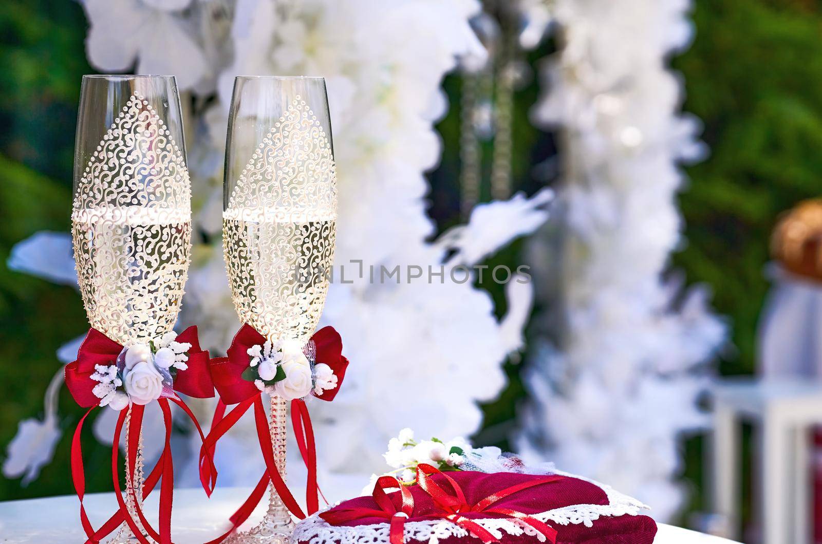 a marriage ceremony, especially considered as including the associated celebrations. Two wedding festive crystal glasses of champagne with red ribbons and wedding decor