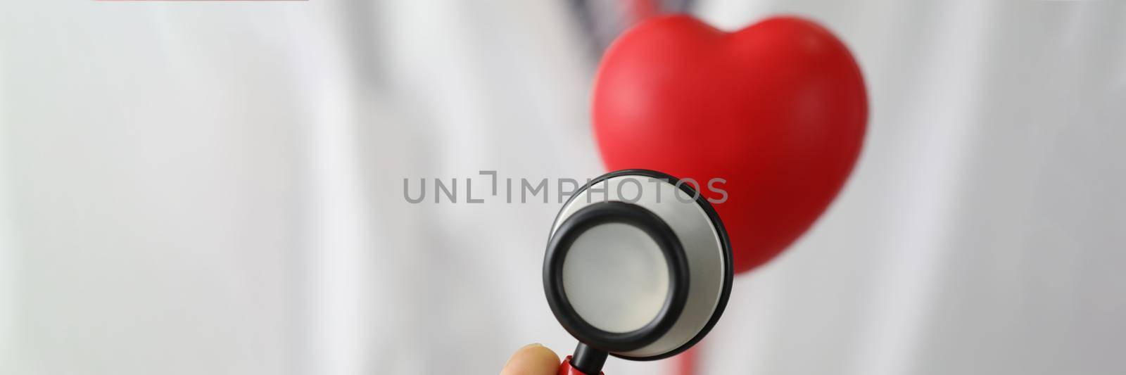 Close-up of medical stethoscope instrument listen to red plastic heart. Save life, full body checkup. Medicine, cardiology, healthcare, analysis concept