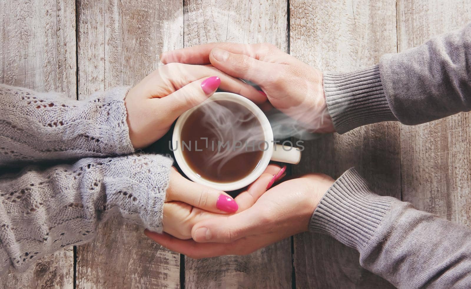 A cup of tea in the hands of a man and a woman. Selective focus. cute.