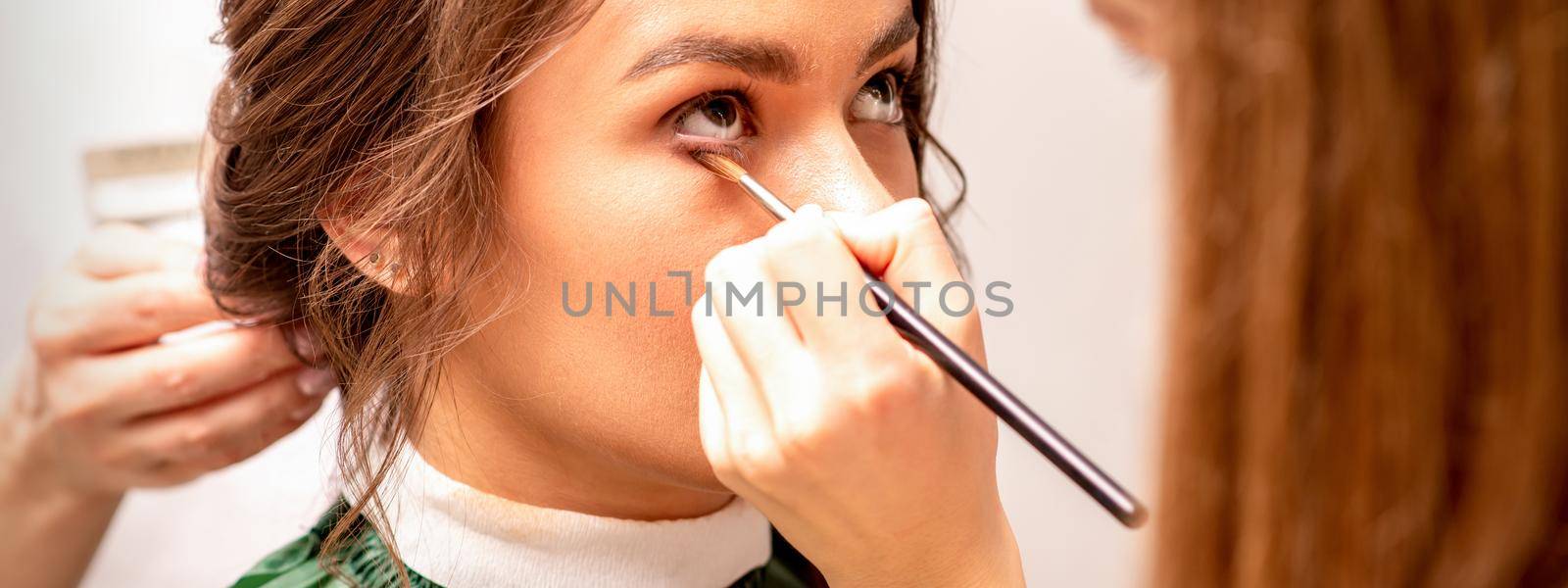 Makeup artist and hairdresser prepare the bride making hairstyle and makeup in a beauty salon