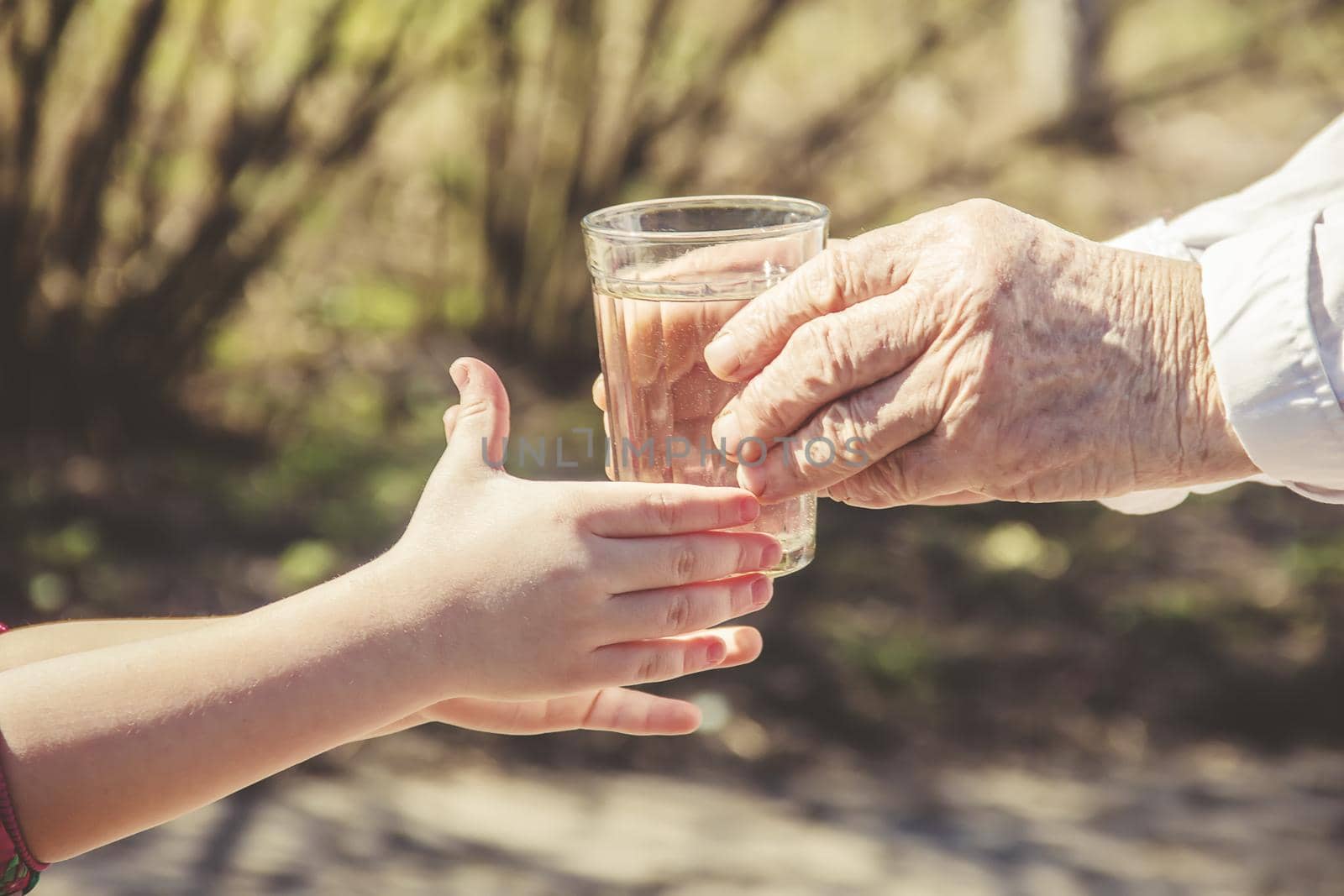 Grandmother giving a glass of clean water to a child. Selective focus.