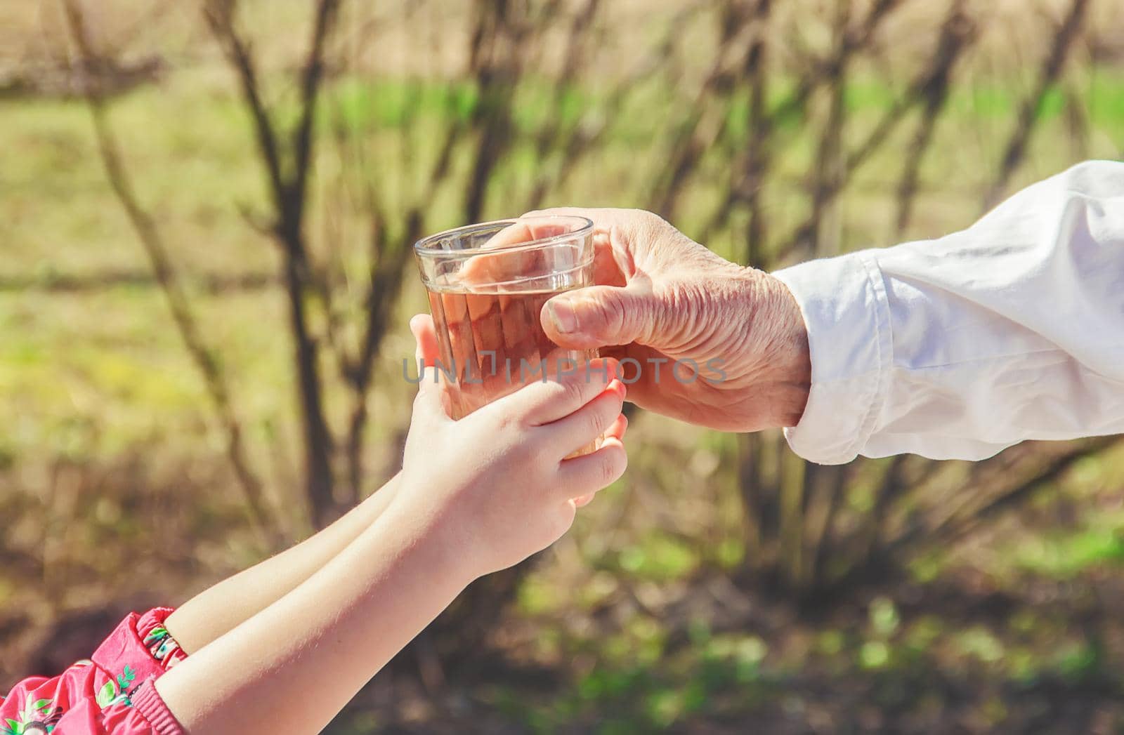 Grandmother giving a glass of clean water to a child. Selective focus.