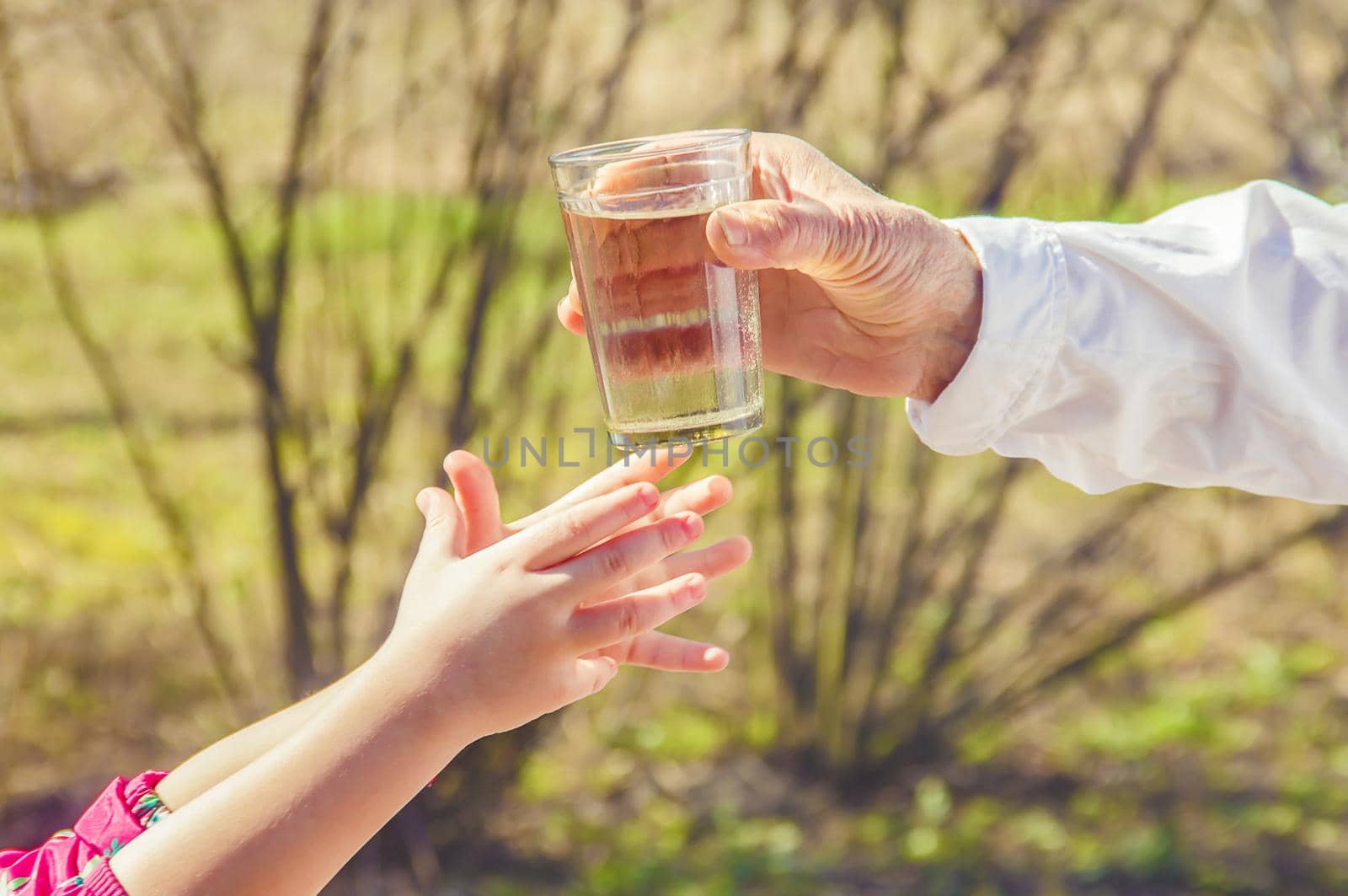 Grandmother giving a glass of clean water to a child. Selective focus. by yanadjana