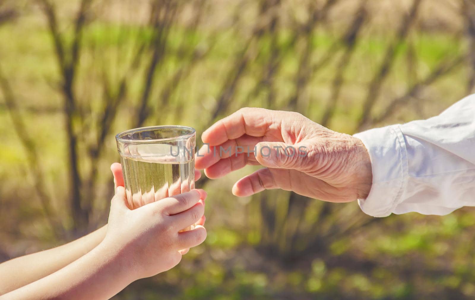 Grandmother giving a glass of clean water to a child. Selective focus.