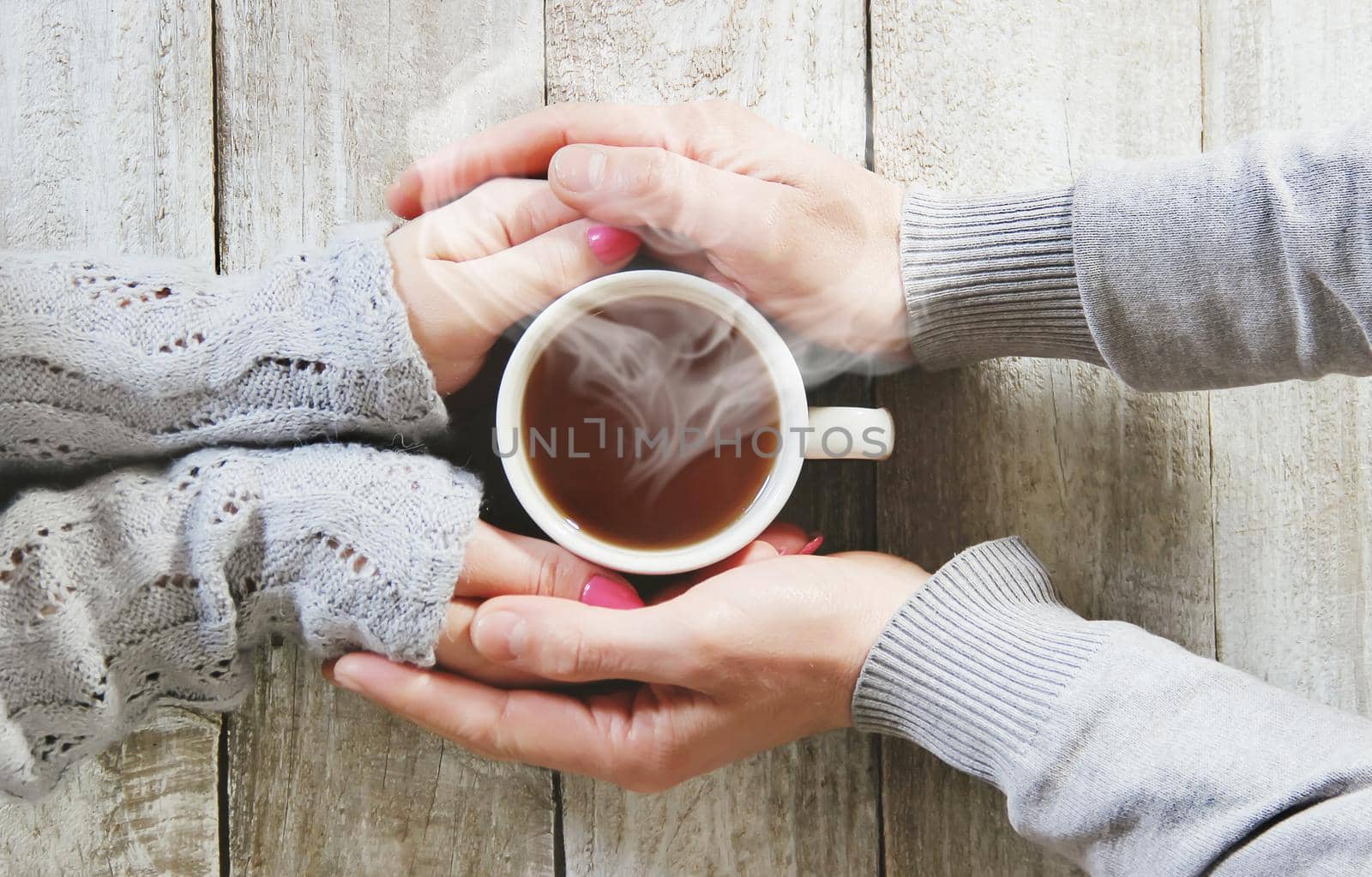 A cup of tea in the hands of a man and a woman. Selective focus. cute.