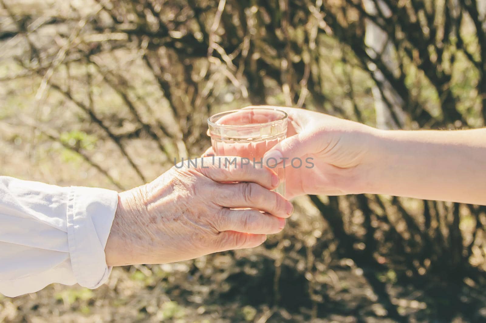 Grandmother giving a glass of clean water to a woman. Selective focus. by yanadjana