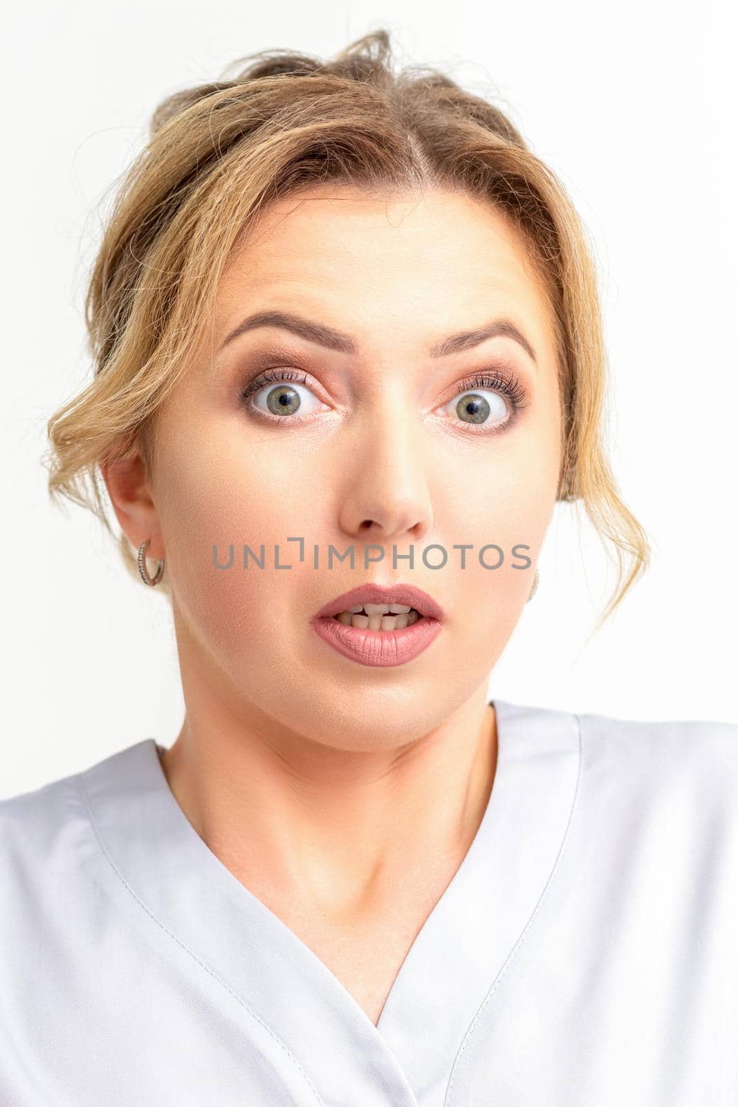 Female doctor shocked. Close up portrait of a young caucasian woman looking surprised with wide eyes stared isolated white wall background. by okskukuruza