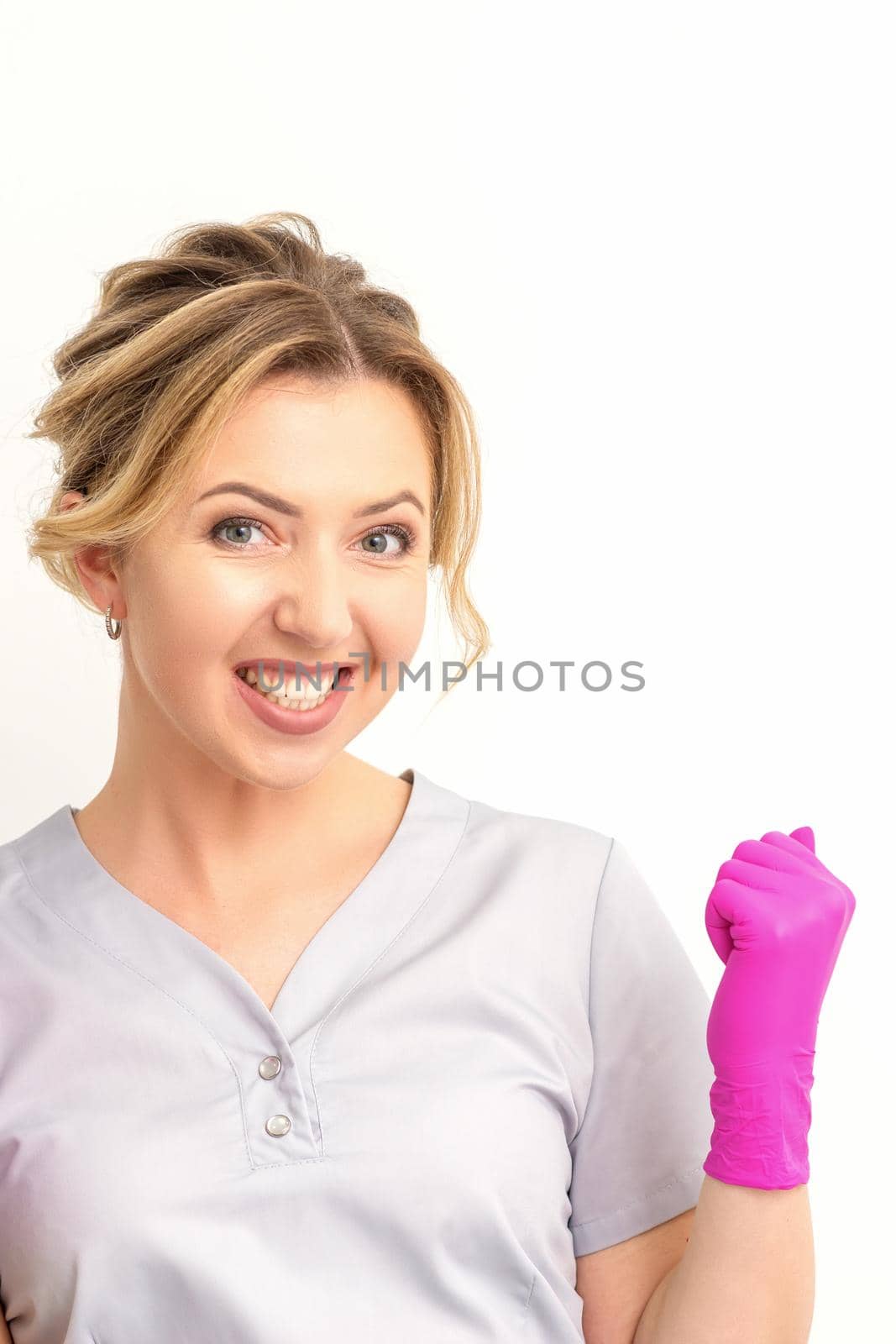 Happy caucasian woman doctor wearing pink gloves celebrates and raising fists on white background