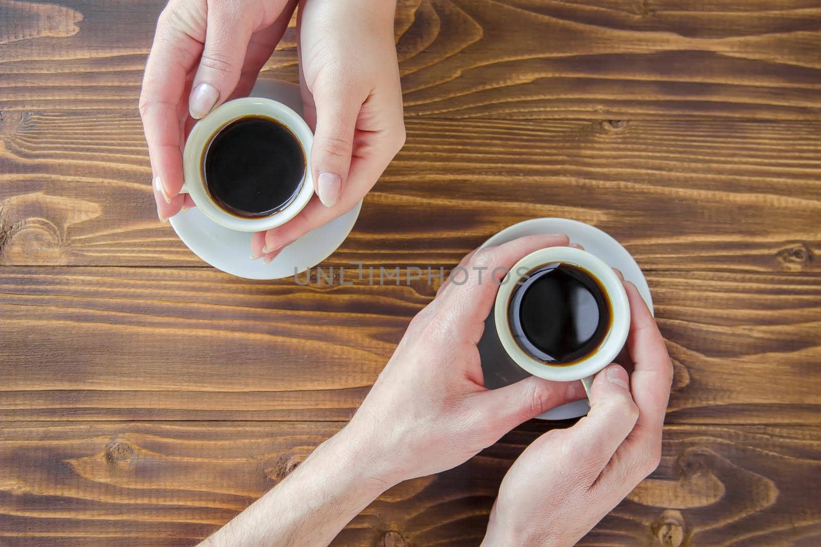 Cups with a coffee in the hands of men and women. by yanadjana