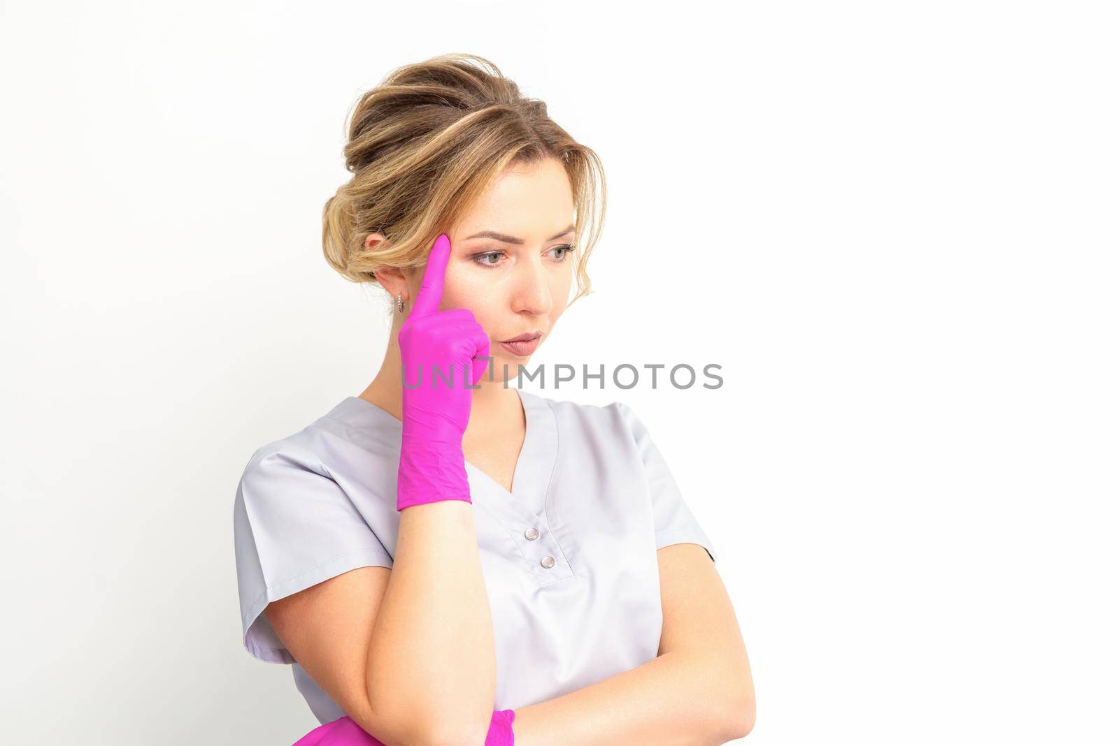 Young caucasian female doctor wearing gloves thoughtful looking away isolated on white background