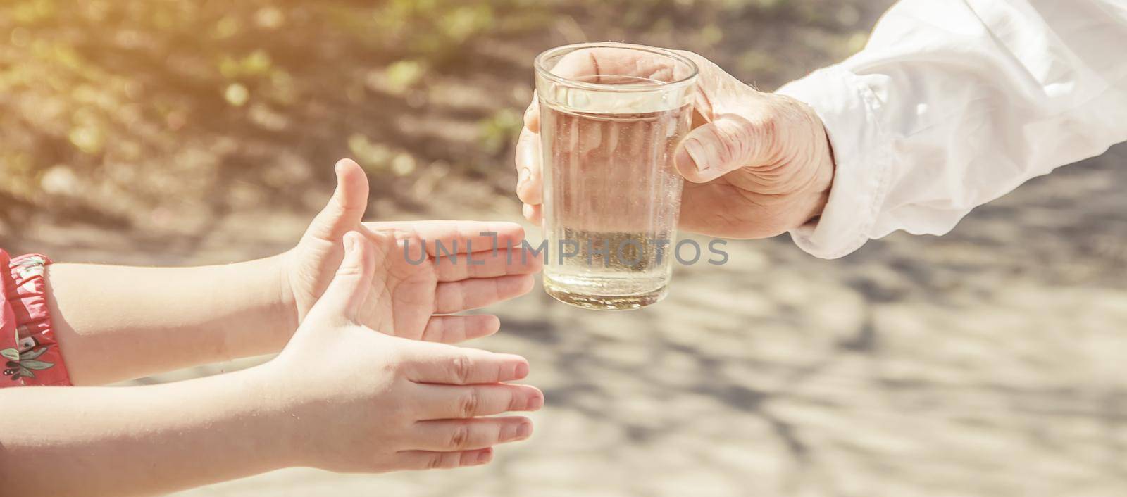 Grandmother giving a glass of clean water to a child. Selective focus. by yanadjana