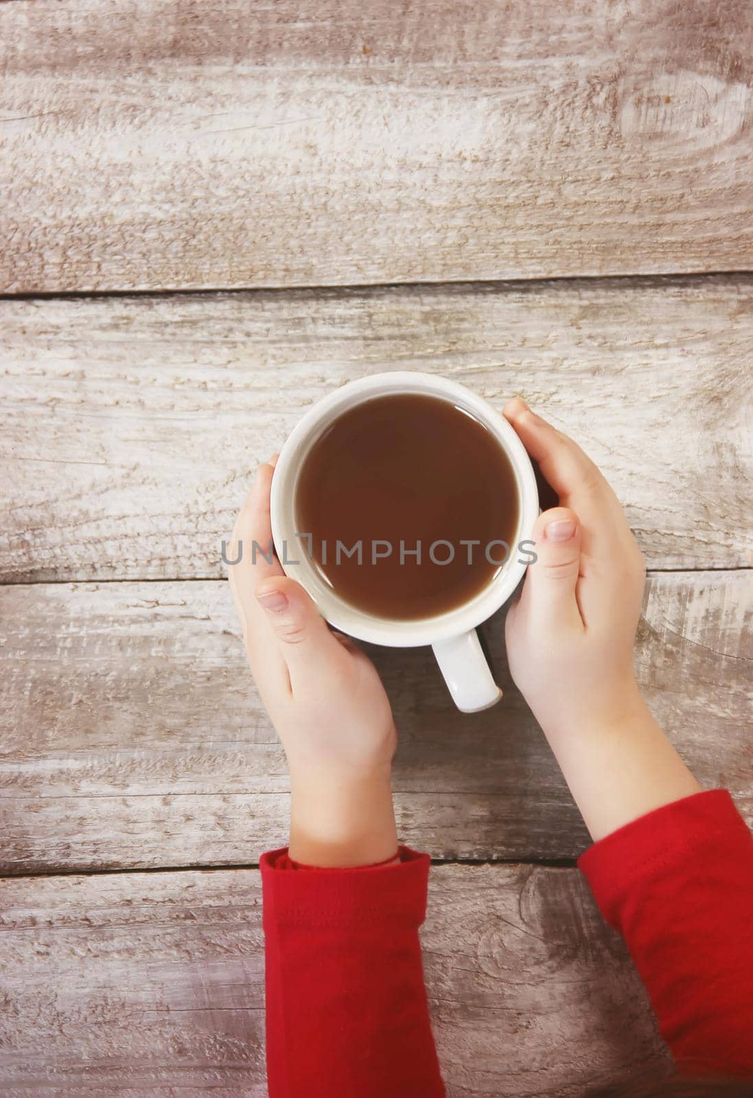 A cup of tea in the hands of a child. Comfort.