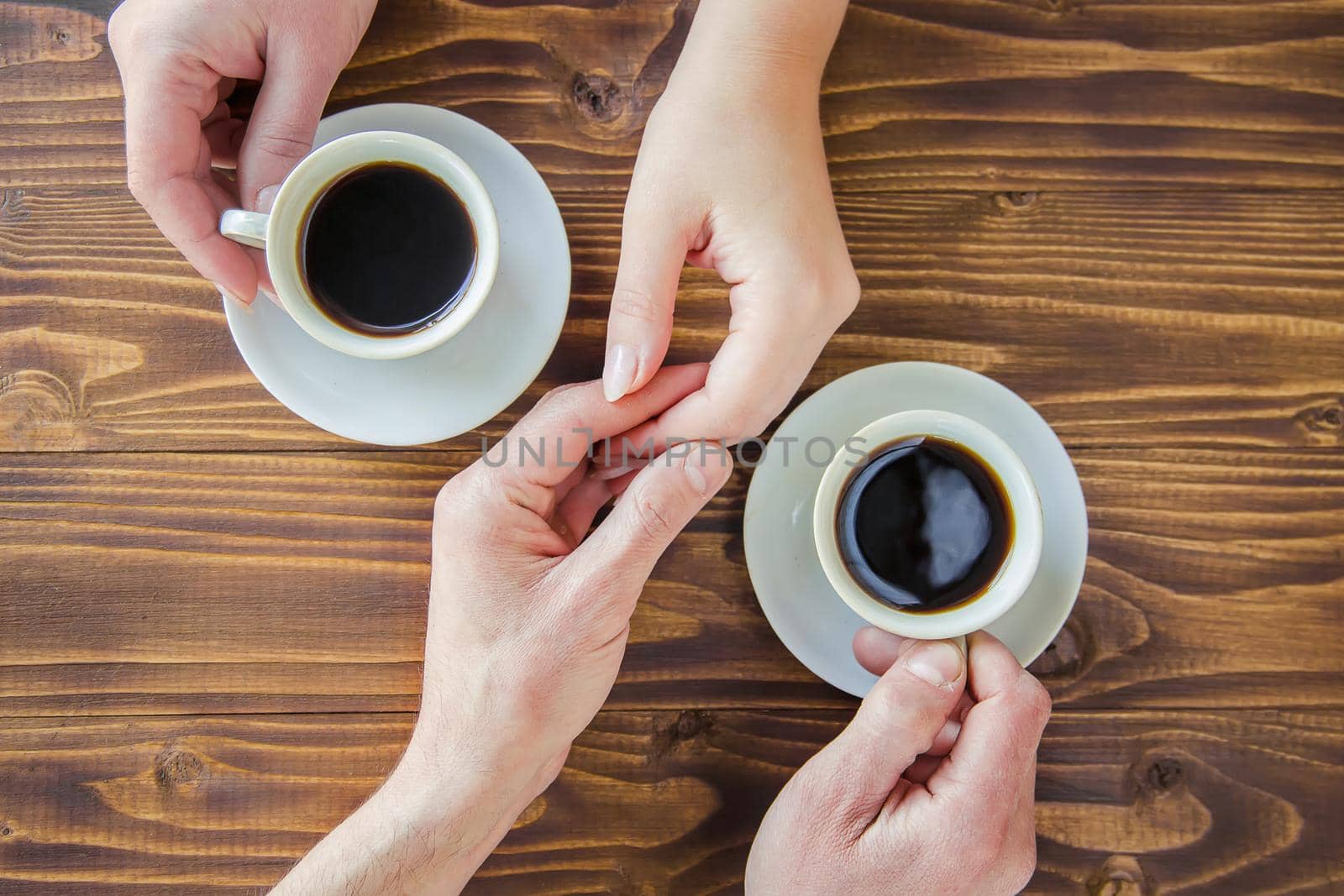Cups with a coffee in the hands of men and women.