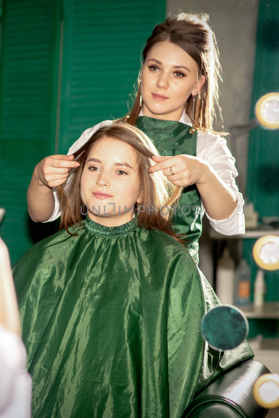 Professional hair care. Beautiful young caucasian brunette woman with long hair receiving hairstyling in a beauty salon. by okskukuruza