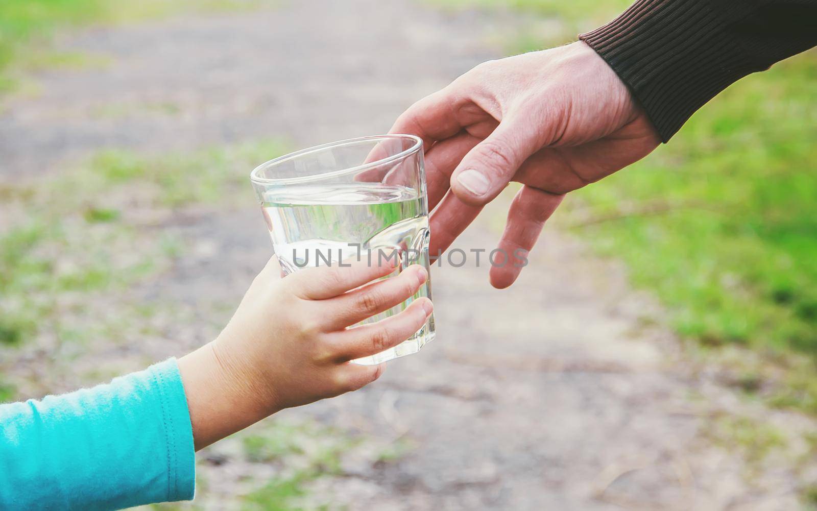 The father gives the child a glass of water. Selective focus.