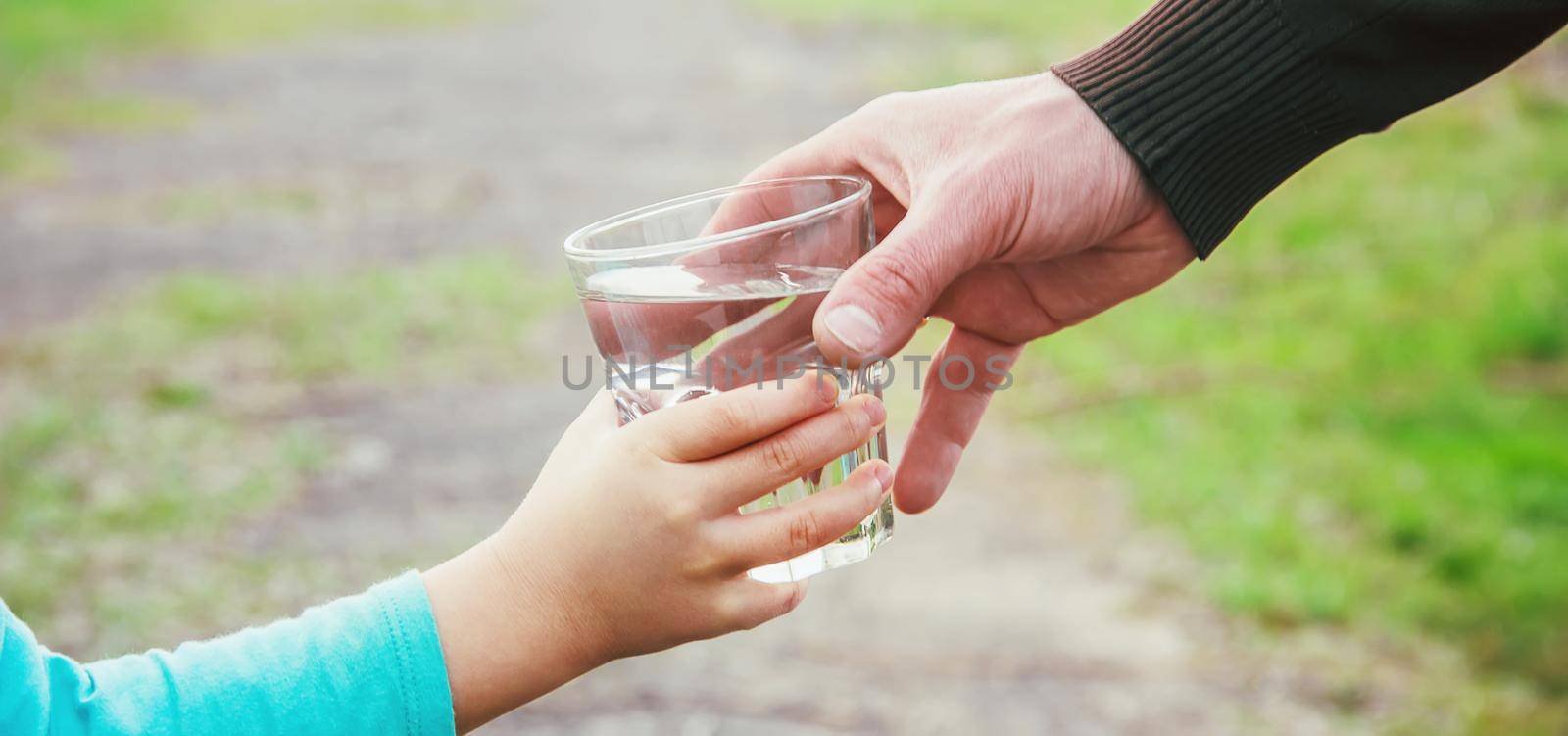 The father gives the child a glass of water. Selective focus. by yanadjana