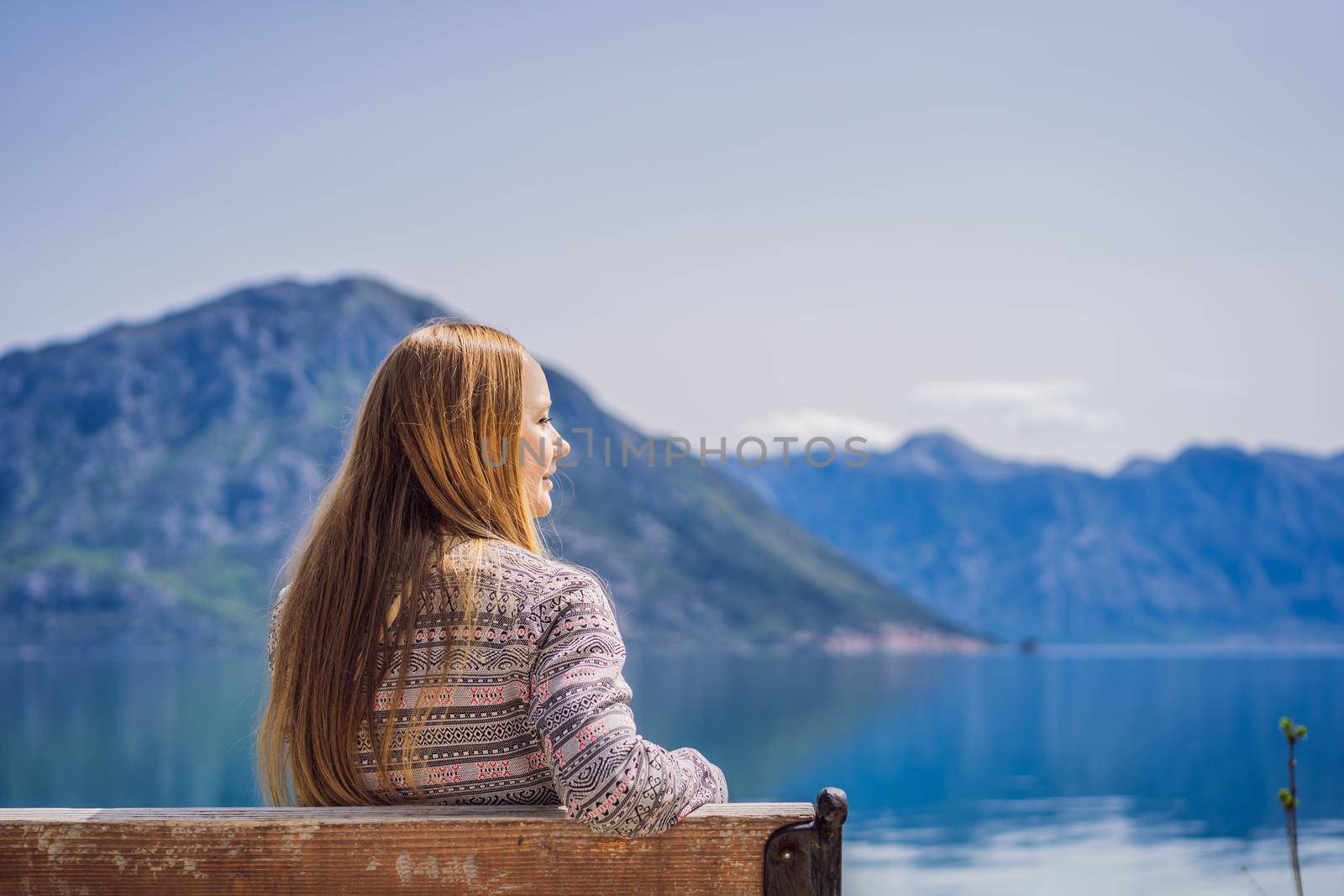 A woman sits on a bench and admires the view of the Bay of Kotor. Montenegro.