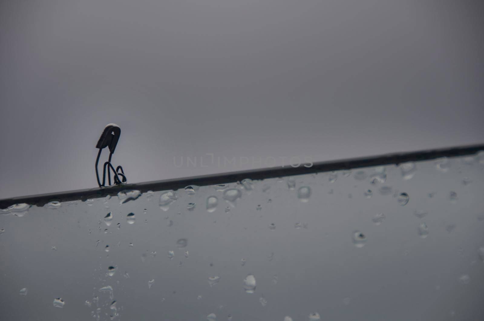 Lonely safety pin sitting on glass wall with customizable space for text and ideas. Lonely concept.