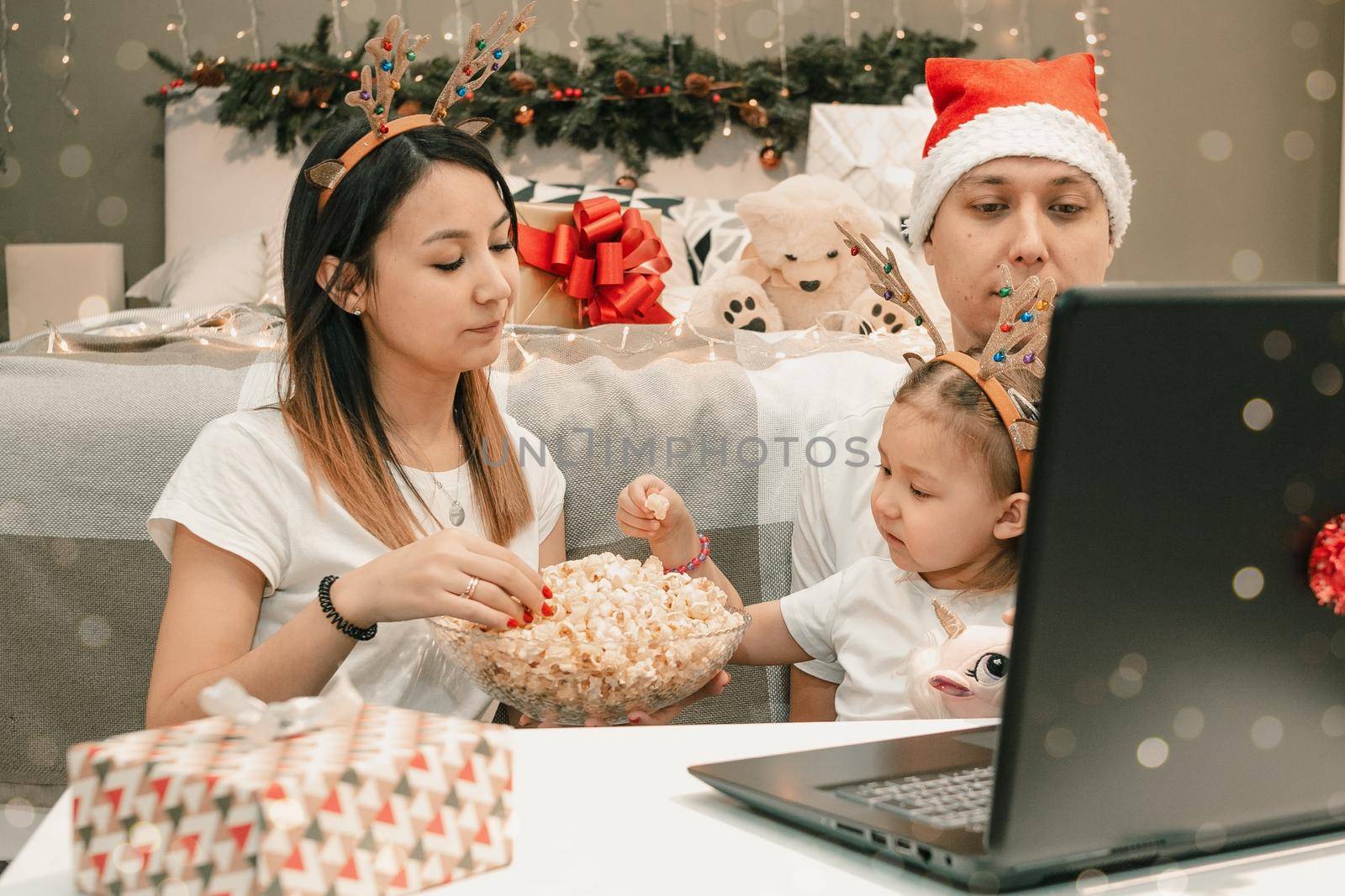 Cozy family christmas with father mother and child girl daughter, watching video on laptop in bedroom, happy fun and xmas holiday together at movie night or via video link, authentic festive lifestyle