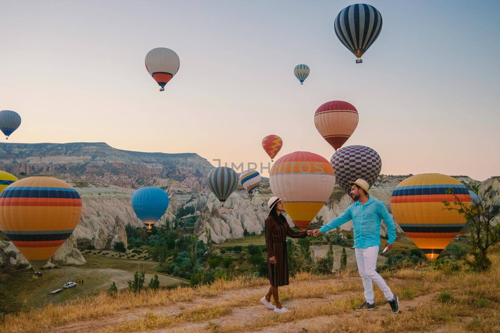 happy young couple during sunrise watching the hot air balloons of Kapadokya Cappadocia Turkey by fokkebok
