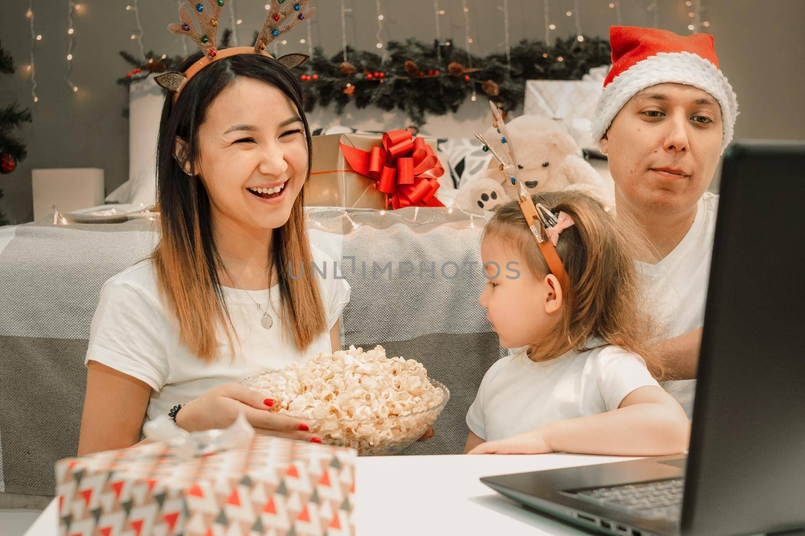 Cozy family christmas with father mother and child girl daughter, watching video on laptop in bedroom, happy fun and xmas holiday together at movie night or via video link, authentic festive lifestyle