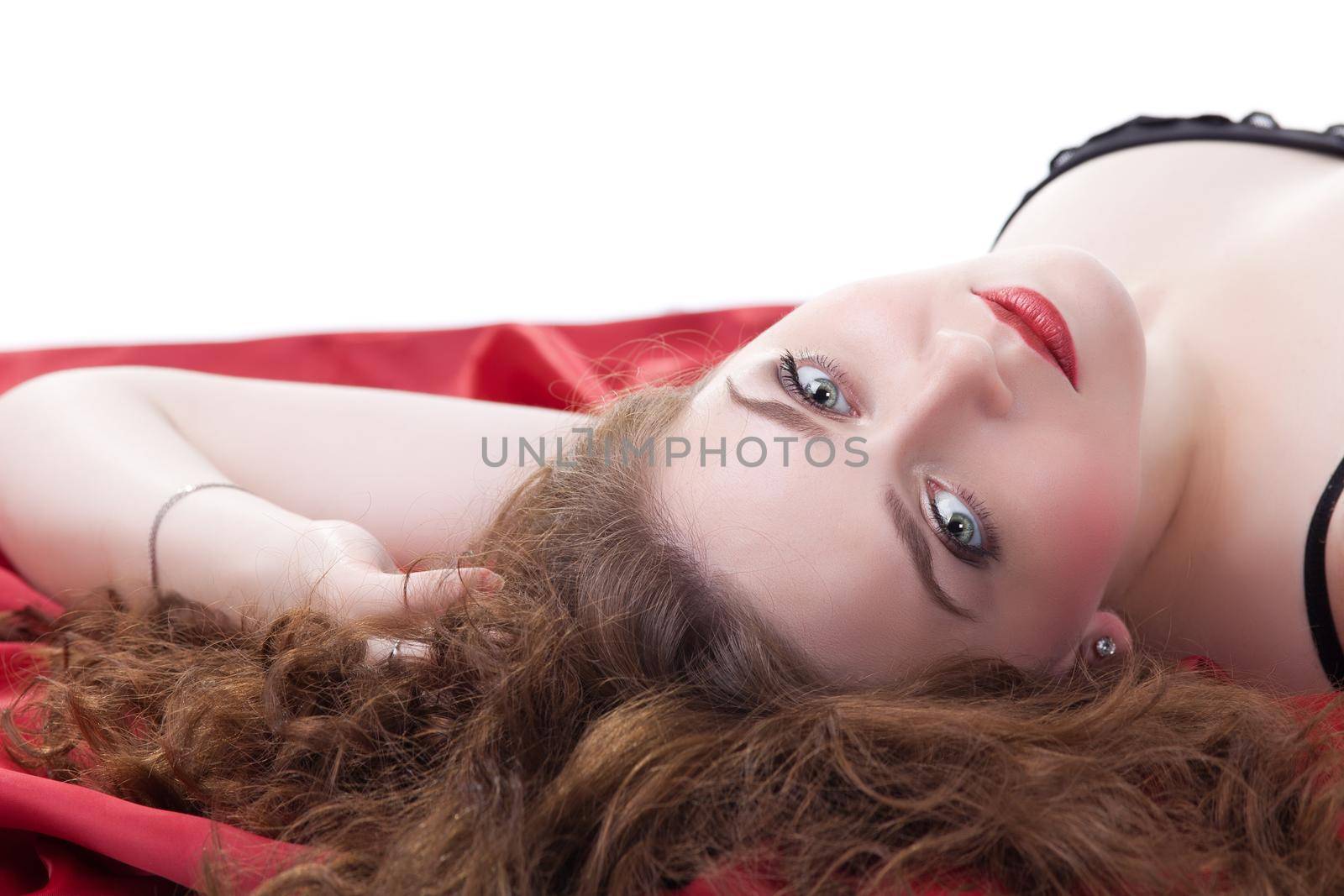 Pretty woman lying on red sheet. Isolated on white