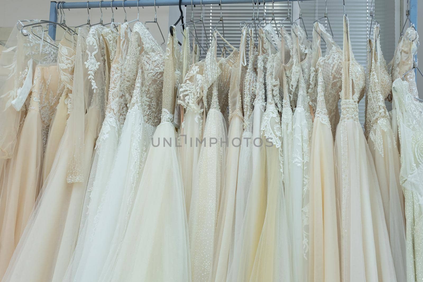White and cream wedding dresses on a hanger in a bridal boutique. Close up.