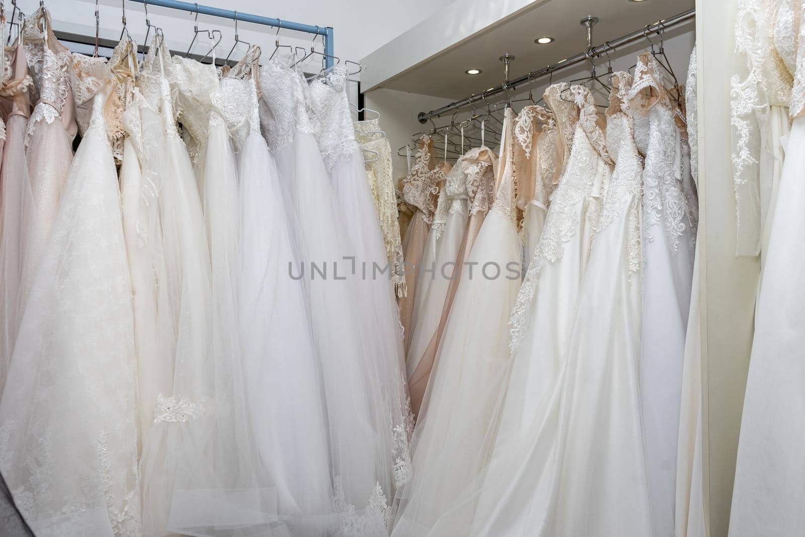 White and cream wedding dresses on a hanger in a bridal boutique. Close up.