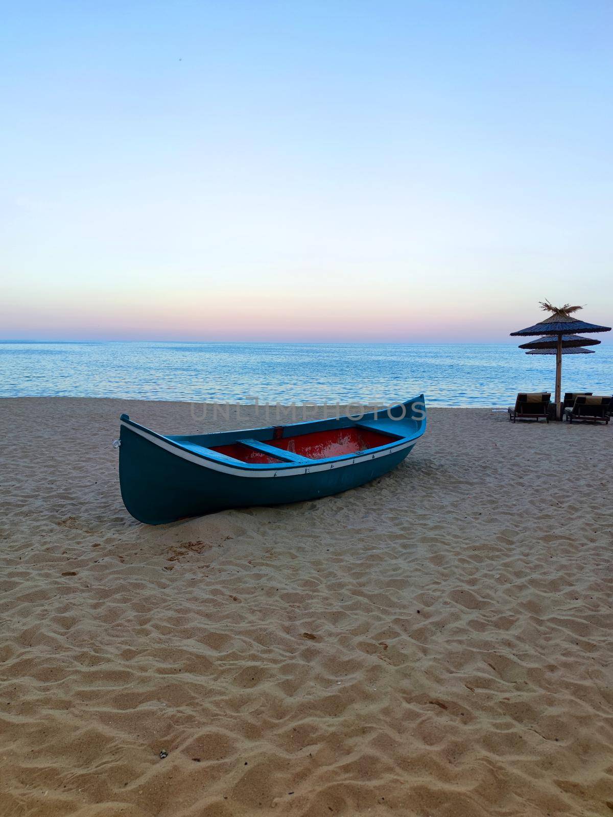 empty old wooden boat on the sand against the background of the sea horizon and sunset sky.