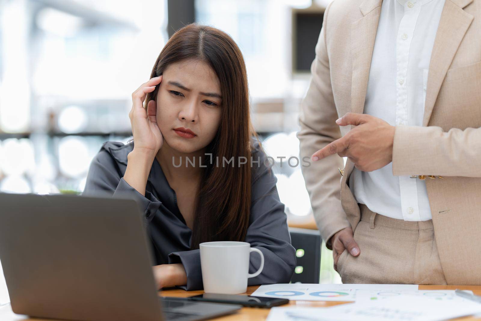 Stressed Asian businesswoman analyzes financial charts. Account and audit concept.