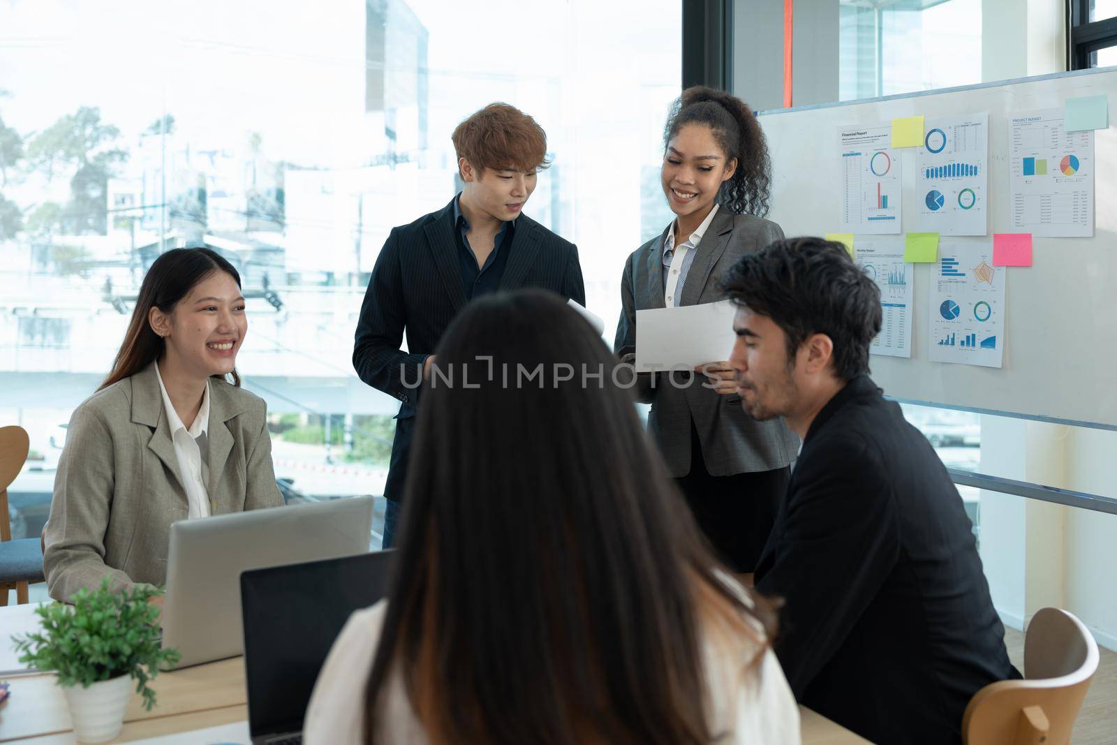 Group of diverse colleagues discussing for financial report with presentation on flipchart during a small conference in the office by nateemee