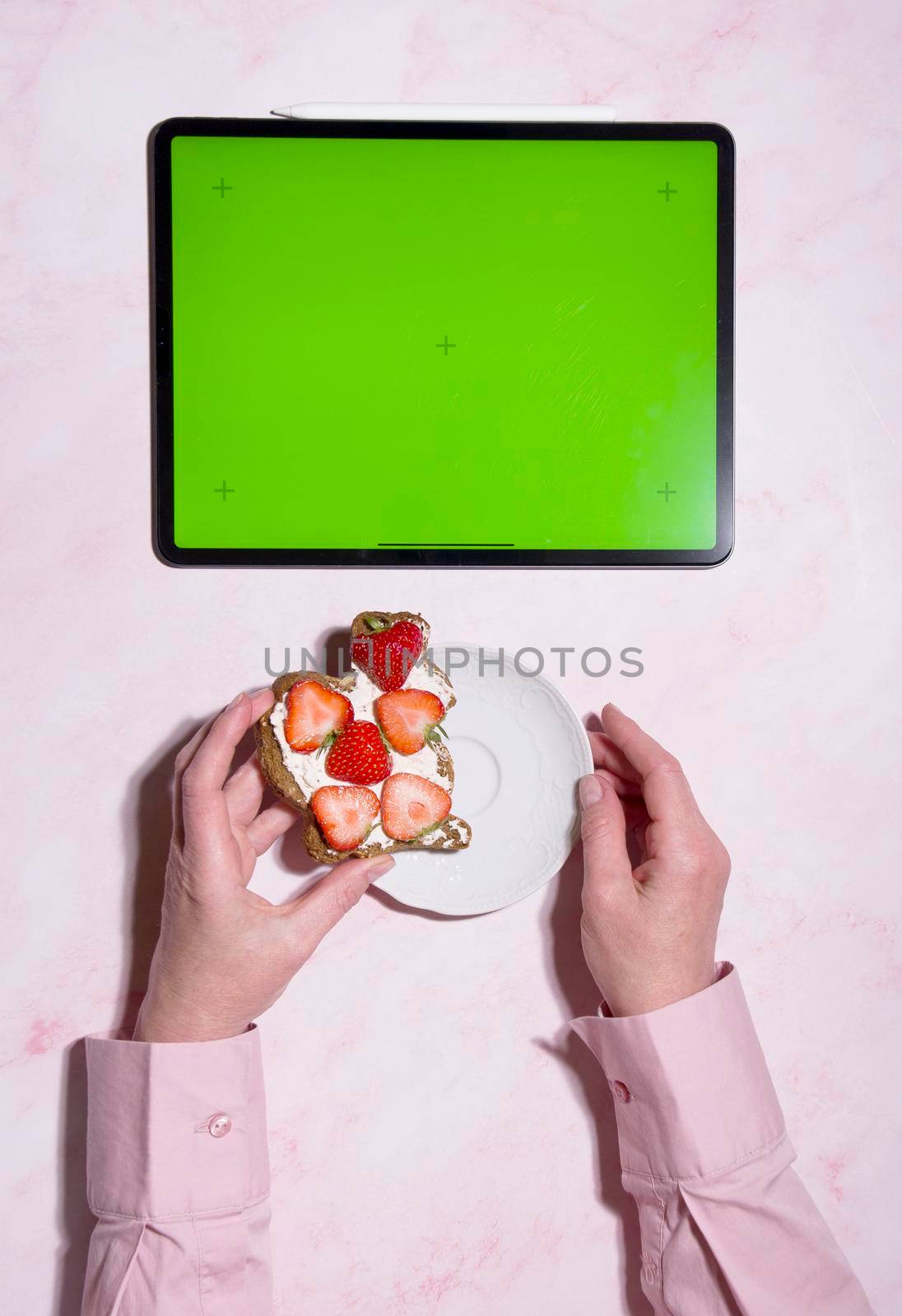 woman holding soft cheese and strawberry sandwich near green screen tablet, concept of healthy food and diet, using calorie counting app, top view, High quality photo