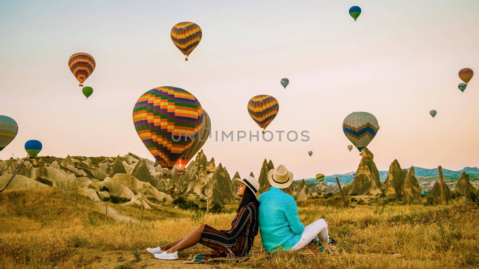 Asian women and caucasian men mid age on a trip to Kapadokya Cappadocia Turkey, a happy young couple during sunrise watching the hot air balloons of Kapadokya Cappadocia Turkey during vacation