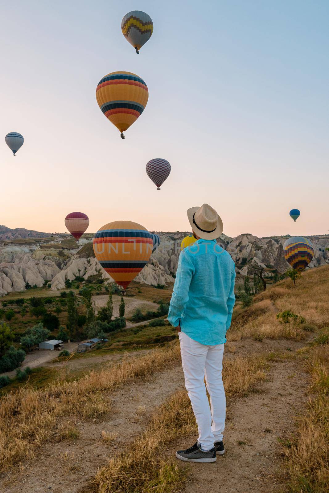 Young men watching hot air balloons during sunrise in Cappadocia Turkey, Kapadokya Goreme. Young caucasian men watching the sunrise in the valley of Cappadocia Turkey