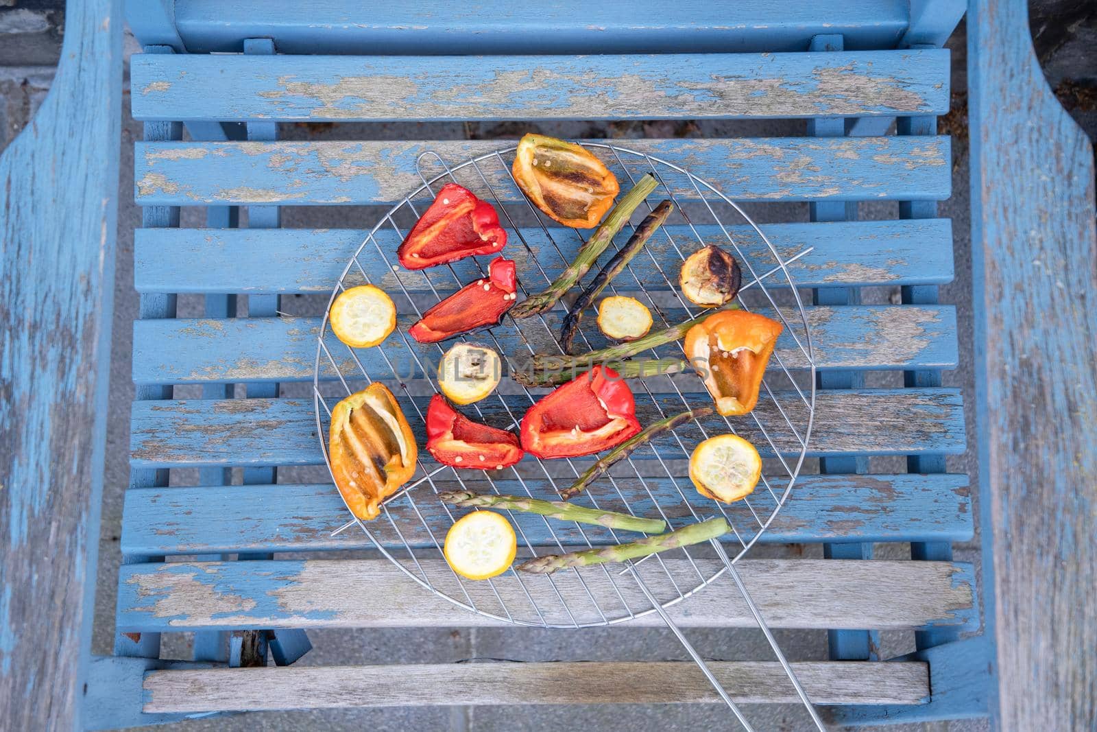 barbecue of colorful raw vegetables on a grill on blue shabby boards, vegetarian food, delicious vegan food, summer picnics. High quality photo
